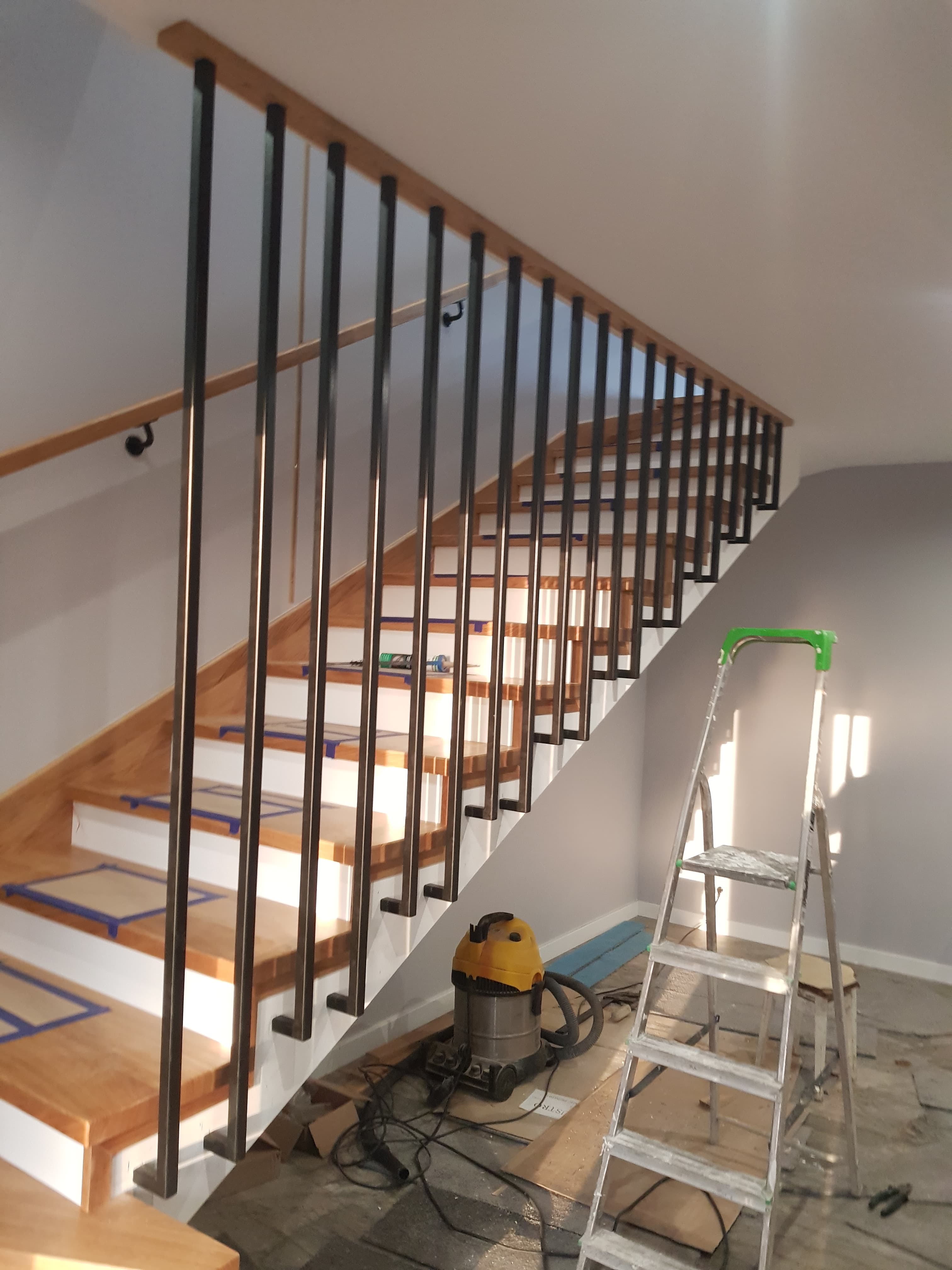 Drewniana klatka schodowa z ciemnymi detalami balustrady.
