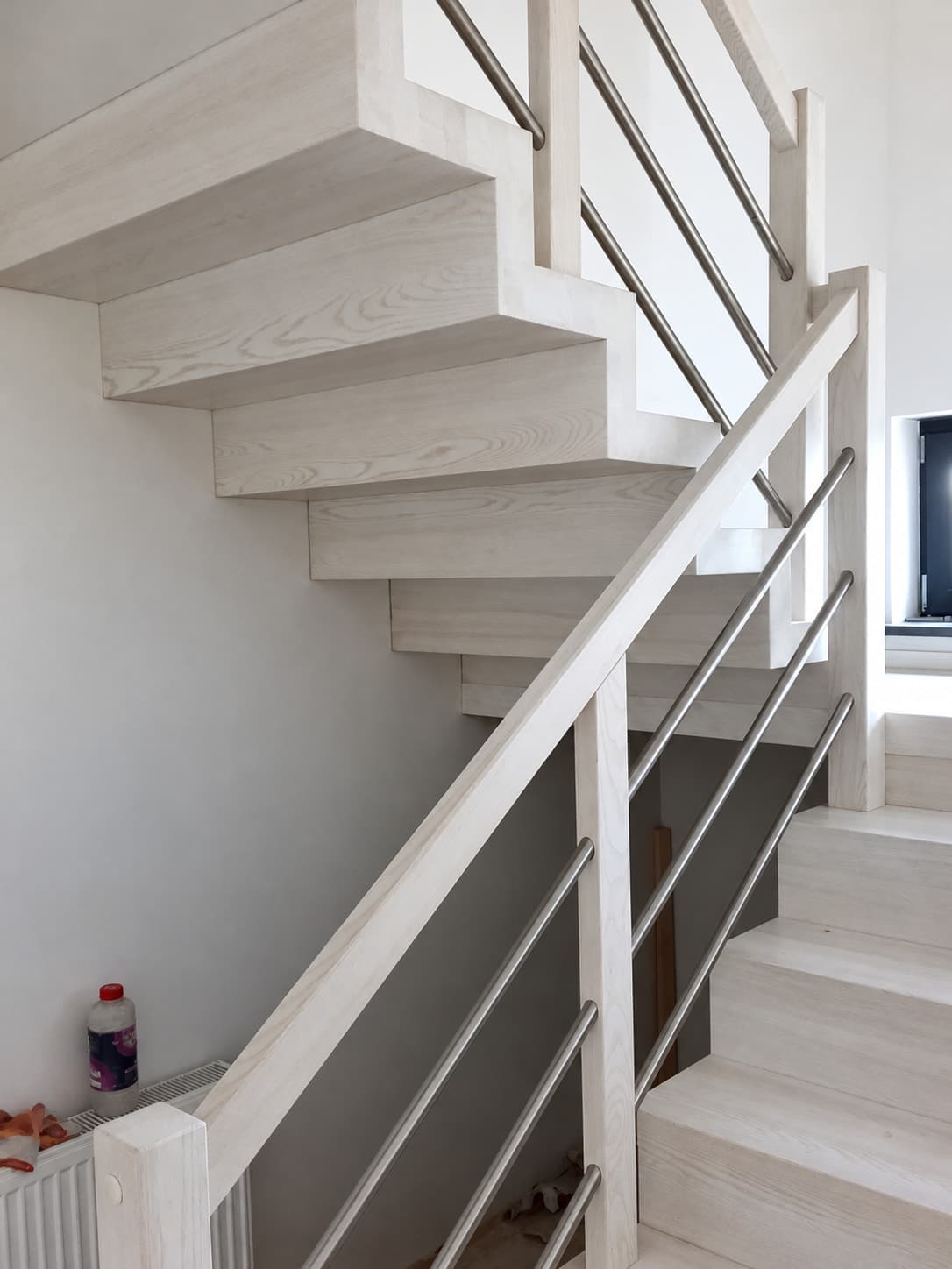 Jasne schody z jasną balustradą przy ścianie.